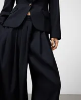 Pantalón sastre de pierna ancha en color azul marino, con pliegues delanteros y cierre cruzado. Incluye bolsillos laterales y bolsillos de vivo en la parte posterior, confeccionado en una mezcla de poliéster, lana merino y viscosa.