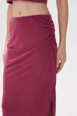 Falda midi de corte tubo confeccionada en modal, con detalle de frunces laterales que aportan movimiento y ajuste al cuerpo.