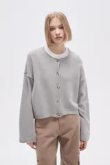 Cardigan de tejido de punto color gris, con cuello redondo, cierre frontal de botones y mangas largas holgadas.