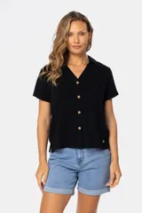 Camisa lisa de lino color beige, de manga corta, con cuello camisero, bolsillo ojal en el pecho y cierre frontal con botones.