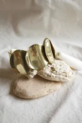 Brazalete rígido dorado con apliques circulares texturizados.