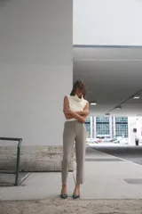 Pantalón tobillero gris oscuro de tiro alto con costuras marcadas en delantero y espalda, bolsillos delanteros de vivo y cierre frontal con cremallera, botón interior y gancho metálico.