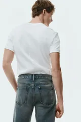 Jean de corte recto en denim de algodón rígido, con diseño de cinco bolsillos y acabado con efecto desgastado.