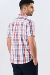 Camisa sport de manga corta con estampa de cuadros, combinando líneas rojas y azules sobre fondo blanco. Posee cuello con botones y cierre frontal abotonado.