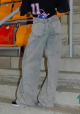 Jean de corte oversize con tiro medio-alto, confeccionado en denim de algodón con lavado tipo ice wash en tono grisáceo. Presenta diseño de cinco bolsillos, cierre frontal y etiqueta de cuero en la parte posterior de la cintura.