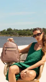 Mochila pequeña de símil cuero color negro, con bolsillo frontal con cierre, asa de mano y correas regulables.