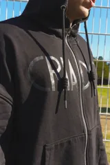 Campera negra de algodón con capucha, cierre frontal con doble cursor y bolsillos laterales. Presenta puños y ruedo tejidos en color celeste. En la espalda, destaca un estampado de un sol con la frase 'De América y del mundo'.