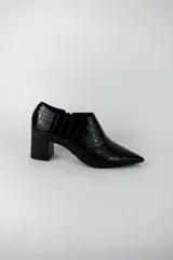 Botines de caña baja con acabado acharolado y textura efecto cocodrilo. Presentan punta fina, cierre lateral y taco cuadrado de altura media.