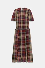 Vestido midi de viscosa con estampado de cuadros escoceses en tonos tierra, burdeos y beige. Presenta cuello redondo, mangas cortas abullonadas, cuerpo con tejido elástico tipo nido de abeja y falda con vuelo con detalle de volante en la cintura. Cierre en la espalda con abertura y lazada.