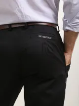 Pantalón de vestir azul marino, de corte recto, con bolsillos laterales y traseros. Se ajusta a la cintura con cinturón de cuero marrón.