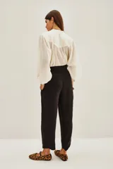 Pantalón sastrero de tiro alto, color blanco, confeccionado en cupro y viscosa. Presenta pinzas delanteras, bolsillos y ajuste elástico en el tobillo.