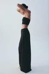 Pantalón de tiro medio color marrón, con pinzas en el delantero, perneras anchas de corte recto y trabillas para cinturón. Cuenta con bolsillos laterales y traseros, y cierre frontal con cremallera y botón.
