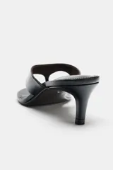 Sandalia de piel con acabado charol en color negro, diseño tipo thong con separación para el dedo, tacón fino medio y punta redonda.