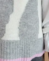 Chaleco tejido de punto con diseño abstracto en bloques de color marrón y turquesa, con cuello redondo y terminaciones acanaladas.