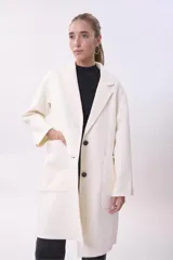 Tapado de lana color crema con solapas clásicas, cierre frontal de dos botones y bolsillos frontales de parche.
