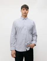 Camisa de manga larga de tejido Oxford color celeste, con cuello button-down, cierre frontal de botones y un bolsillo aplicado en el pecho.