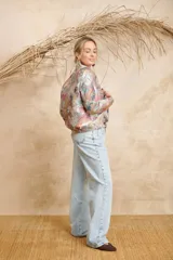 Bomber estampada con diseño abstracto multicolor, cuello mao y cierre frontal con botones dorados.