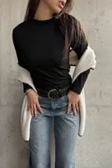 Remera negra de cuello alto y manga larga, confeccionada en tejido de algodón con textura acanalada.