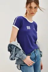 Remera estilo ringer, color azul oscuro con cuello y ribetes en las mangas en color blanco. Presenta el número "99" estampado en blanco en el frente.