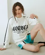 Buzo de punto blanco con líneas negras en las mangas y la inscripción "MANDINGA AUTOCTONOS URUGUAYOS SINCE 2011" en el frente.