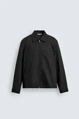 Sobrecamisa negra de corte relajado, confeccionada en tejido con mezcla de algodón elástico. Presenta cuello solapa, cierre frontal de cremallera, bolsillos de plastrón en el pecho y bolsillos de vivo en la cadera.