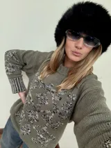 Buzo de tejido de punto grueso color marrón con diseño geométrico y floral estampado en color rojo. Presenta cuello redondo, mangas largas y puños y ruedo acanalados.