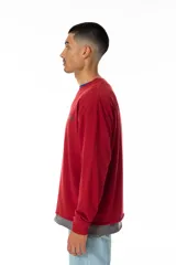 Buzo rojo de jersey doble 100% algodón, con corte levemente boxy y logo frontal serigrafiado en estilo graffiti. Costuras negras visibles y cuello redondo con ribete azul. Hecho en Uruguay.