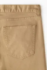 Pantalón de sarga de algodón con diseño de cinco bolsillos, cierre frontal con botón y corte ajustado.