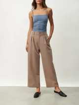 Pantalón de vestir color tostado de corte ancho y relajado, tiro alto con trabillas para cinturón, pinzas frontales y bolsillos laterales.