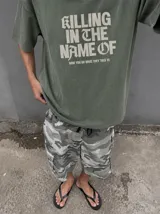 Remera gris con efecto acid wash y diseño oversize. Presenta un estampado frontal con la inscripción "KILLING IN THE NAME OF" y la frase "NOW YOU DO WHAT THEY TOLD YA".