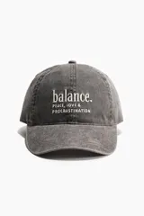 Gorra de sarga de algodón gris con efecto lavado, visera curva y diseño bordado en el frente con la frase "balance. PEACE, LOVE & PROCRASTINATION".