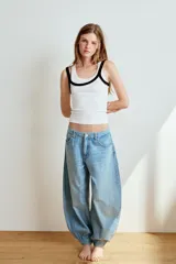 Jeans de tiro medio y diseño balloon, color azul denim con efecto lavado, cinco bolsillos, cierre frontal con cremallera y botón metálico, y bajos acabados en puño.