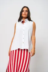 Camisa blanca sin mangas con cuello mao adornado con un delicado volado y cierre frontal con botones.