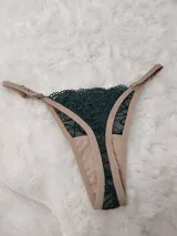 Microtanga con frente de encaje verde oscuro con diseño ornamental y laterales regulables en color beige.