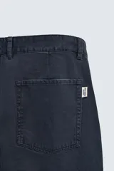 Pantalón de corte carrot fit confeccionado en tejido de algodón con estructura diagonal y efecto lavado. Presenta bolsillos frontales con bolsillo cerillero, bolsillos traseros de plastrón y cierre frontal con cremallera y botón.