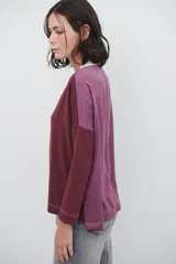 Remera de manga larga color bordó con cuello redondo en contraste color crema y costuras decorativas visibles en el ruedo y puños.