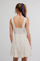 Vestido corto de poliéster color blanco con tejido calado tipo eyelet, sin mangas, con pronunciado escote en V, cuerpo ajustado y falda acampanada.