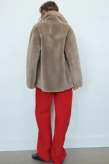 Abrigo reversible de corte recto con cuello solapa, manga larga y cierre frontal de doble botonadura. Presenta un diseño de efecto pelo en un lado y efecto piel en el reverso, con bolsillos de plastrón en el frente.
