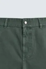 Bermuda tipo jorts de algodón color verde oscuro, con corte relajado y tiro medio. Presenta bolsillos frontales y bolsillos traseros de plastrón.