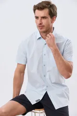Camisa de manga corta de algodón en color celeste con microdiseño geométrico a cuadros, cuello camisero y bolsillo frontal con logo bordado.