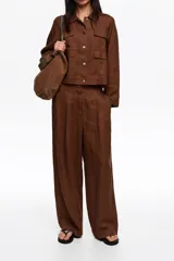 Pantalón de lino color marrón de corte recto y tiro medio, con bolsillos laterales y pinzas delanteras.
