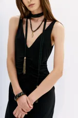 Vestido largo al tobillo de color negro, con escote pronunciado en V y diseño al cuerpo. Presenta detalles drapeados tanto en el frente como en la espalda, confeccionado en una mezcla de poliéster y elastano.