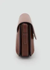 Bolso de hombro tipo bandolera en color marrón, con diseño estructurado de solapa, cierre metálico a presión y costuras decorativas en contraste. Incluye correa larga ajustable.