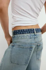 Jeans de tiro medio con cinco bolsillos, cintura doble a contraste y detalles de rotos. Cierre frontal con cremallera y botones metálicos.