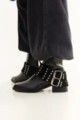 Bota de caña baja con textura tipo crocco, taco cuadrado y punta cuadrada. Incluye un accesorio desmontable con doble hebilla metálica y tachas decorativas.