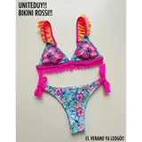 Bikini de dos piezas con estampado floral tropical sobre fondo celeste. El corpiño es de estilo triángulo con volados naranjas en los breteles y una banda inferior fucsia con detalle de puntilla. La bombacha es de corte tanga con tiras laterales ajustables en color fucsia.