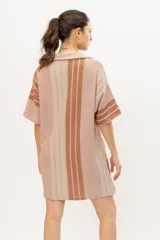 Camisola tipo vestido tejido en algodón con lurex a rayas verticales en tonos marrones, con cuello camisero, mangas cortas y cierre frontal con botones.