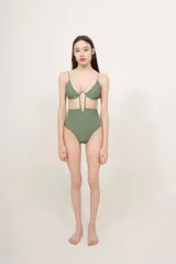 Malla enteriza negra con diseño cut-out frontal, que conecta el corpiño con la parte inferior mediante tiras verticales. Presenta un corte de tiro alto y escote con aros.