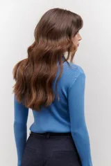 Polera de tejido morley color azul, con cuello alto y mangas largas, de corte ajustado al cuerpo.