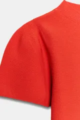 Top de punto color blanco, de cuello redondo y manga corta abullonada.